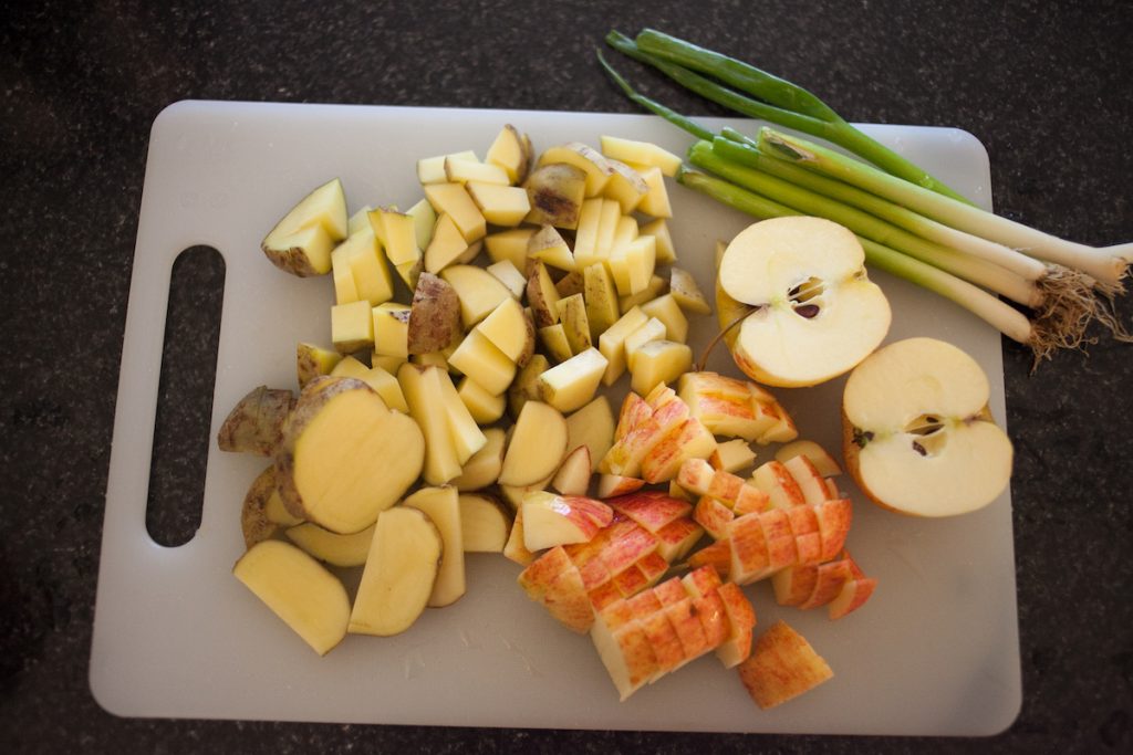 potatoes, apples, and spring onions on chopping board for one month meal plan