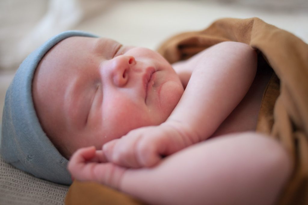 baby sleeping with hands up by face