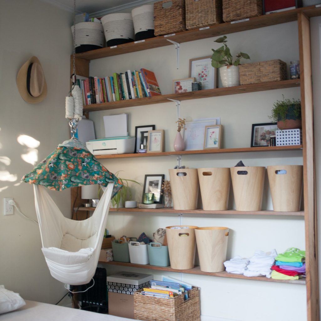 baby hammock hanging in parents room next to shelves to make a tiny nursery space