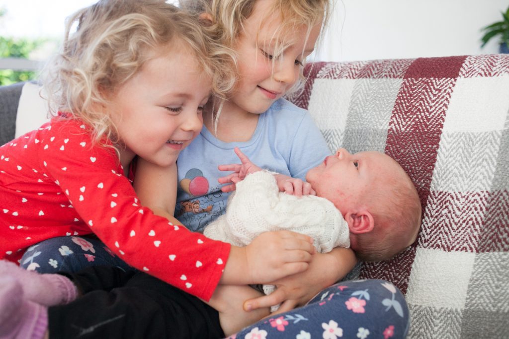 sisters holding newborn baby