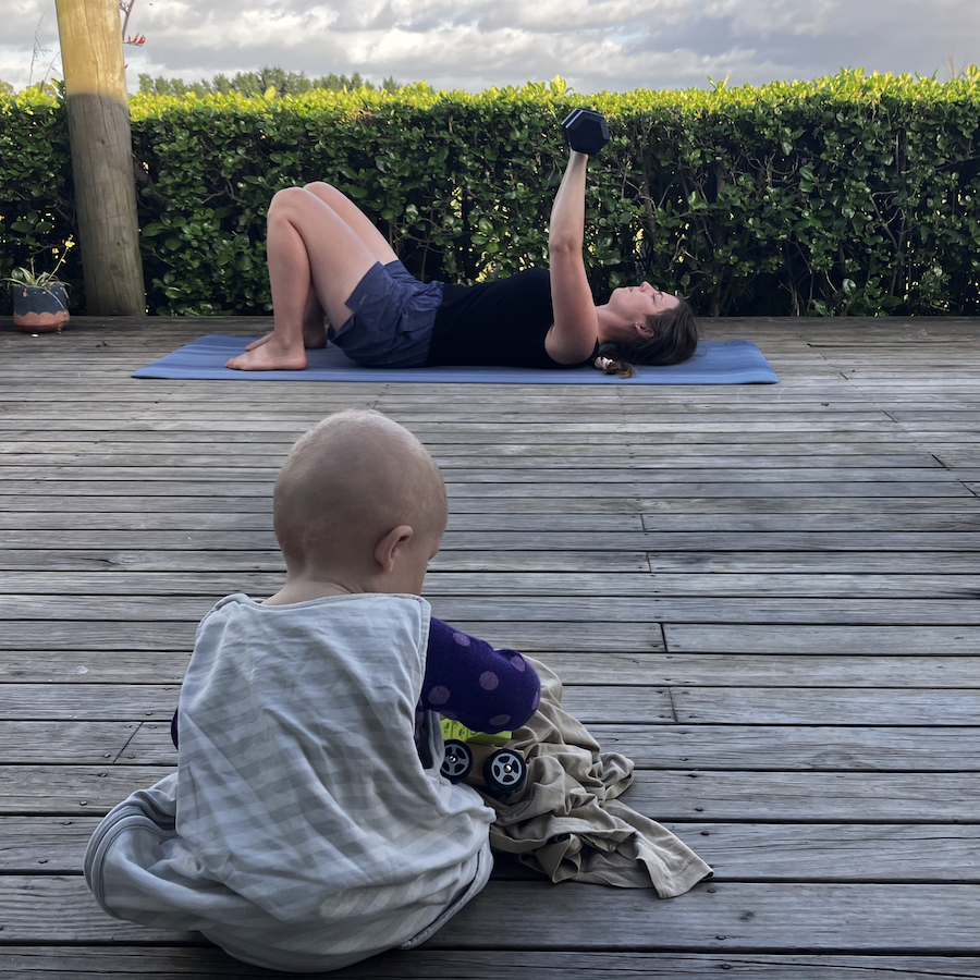 mom working out during her morning routine with baby self entertaining nearby