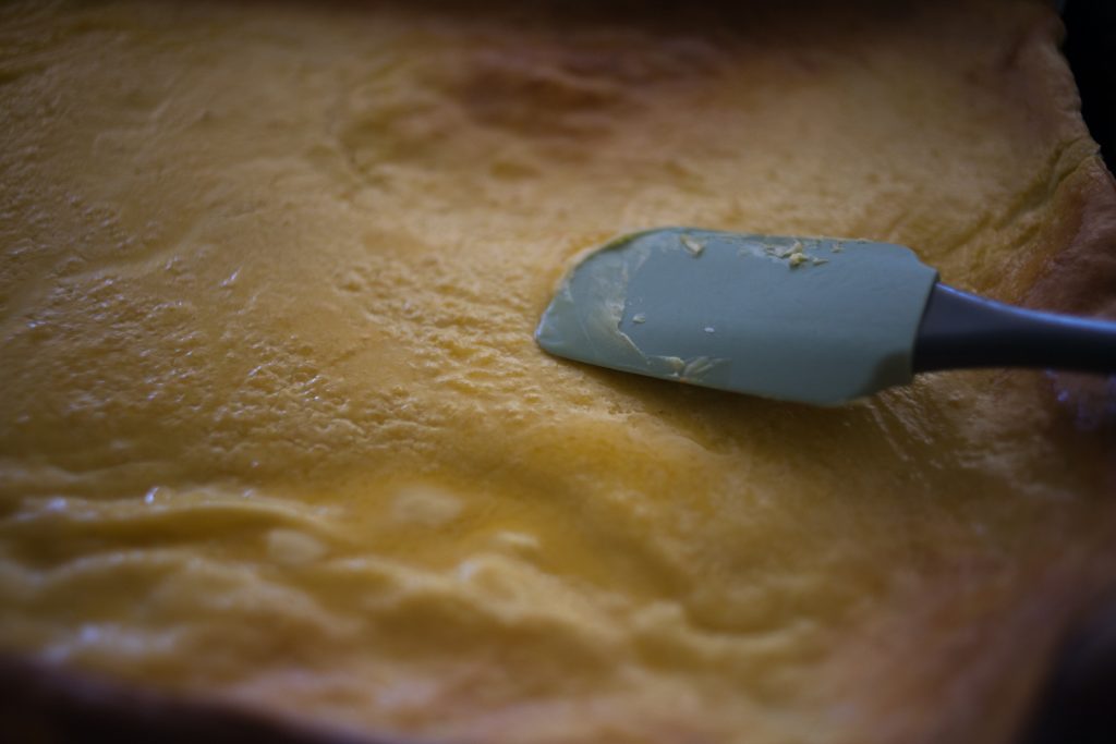 spatula spreading butter on sheet pan Swedish Pancakes