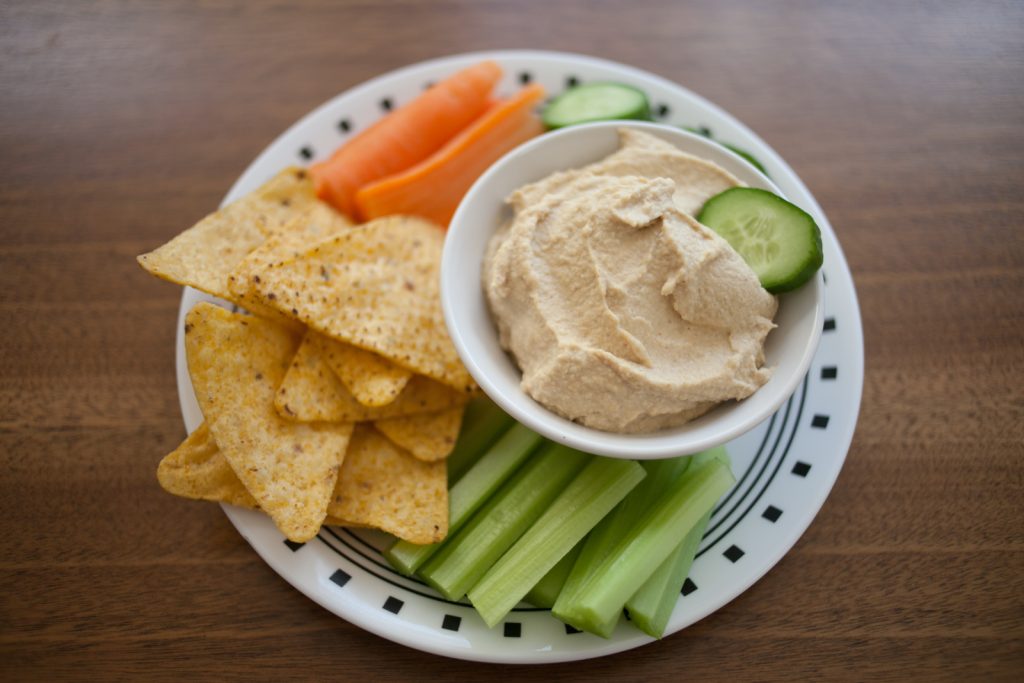 bowl of simple hummus on plate with veggies and chips