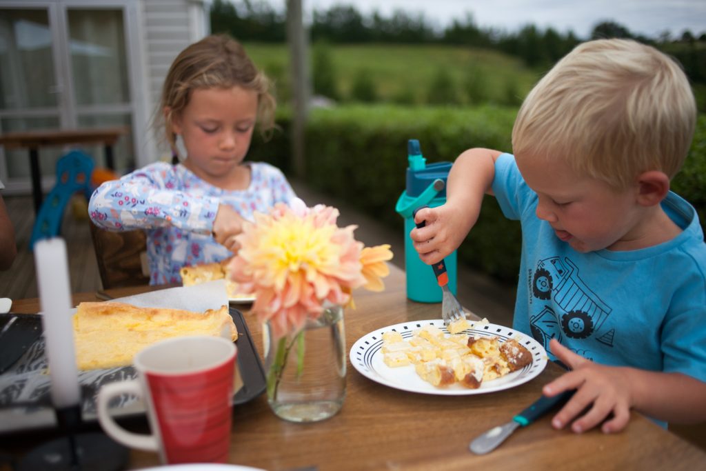 Boy and girl sitting at table eating sheet pan Swedish Pancakes