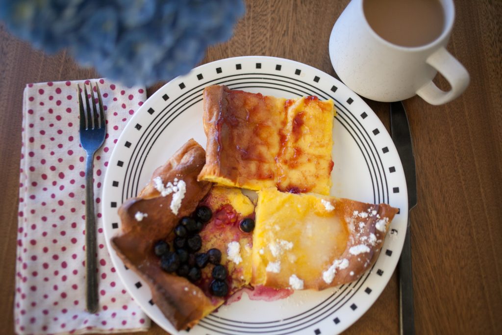 table setting with sheet pan Swedish pancakes on plate and cup of coffee