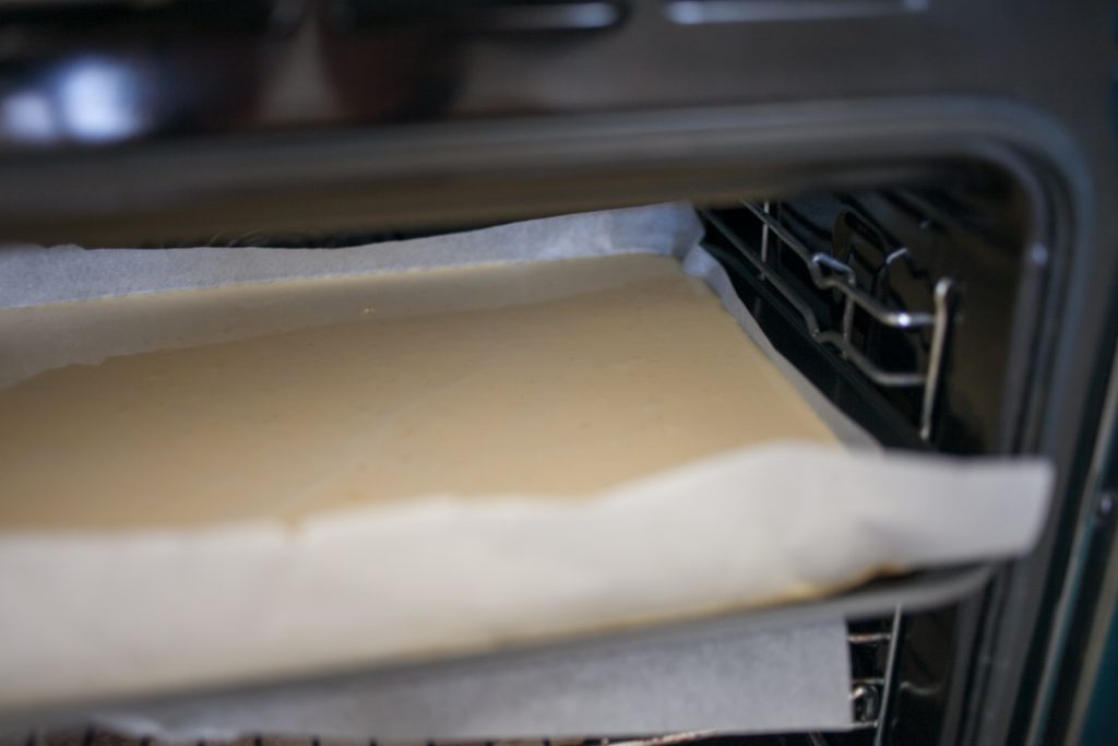 Sheet Pan Swedish Pancake Batter in baking paper on baking sheet in oven