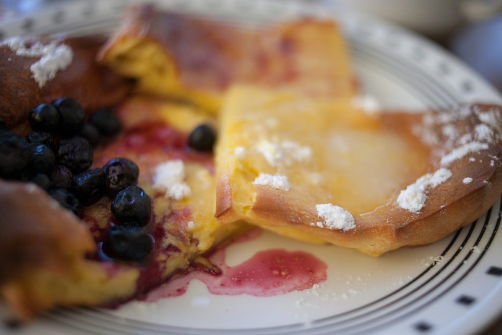 blueberries, lemon and powdered sugar, and jam toppings on slices of Sheet Pan Swedish Pancakes