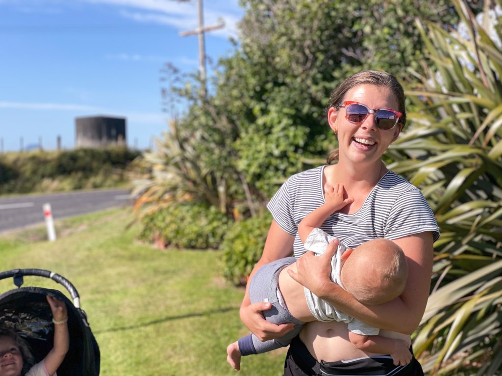 mom breastfeeding baby wearing sunglasses while walking alongside a road