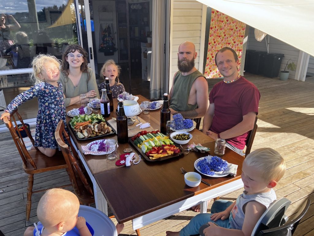 group of adults and kids around table outside eating dinner