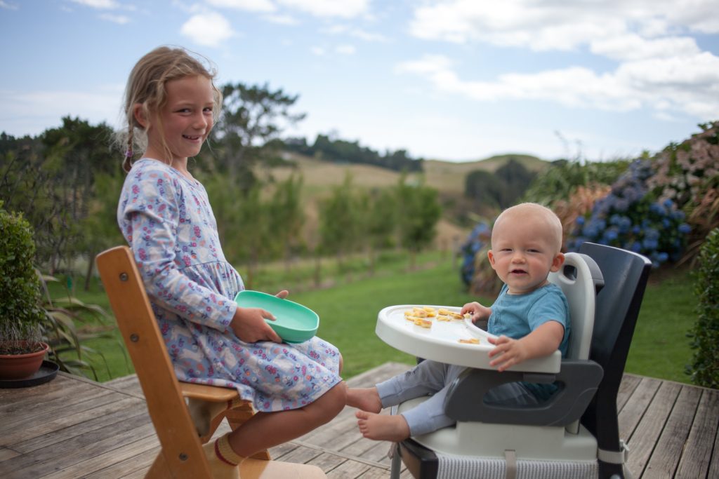 girl feeding brother during daily summer routine outside on deck