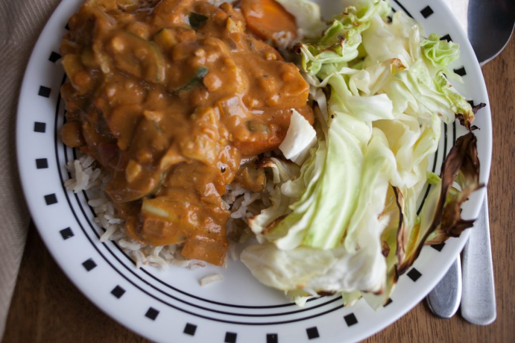 overhead view of white and black plate with peanut butter curry and roasted cabbage meal