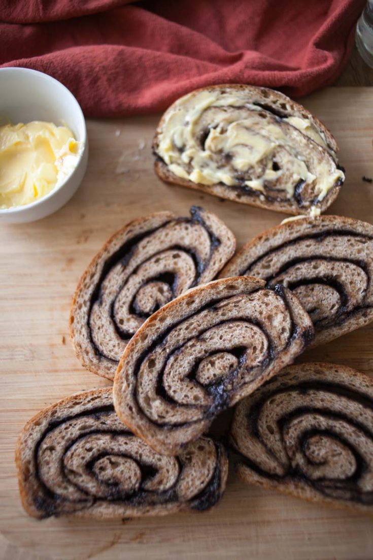 six slices of sourdough chocolate chai swirl bread on cutting board, with one of slices buttered