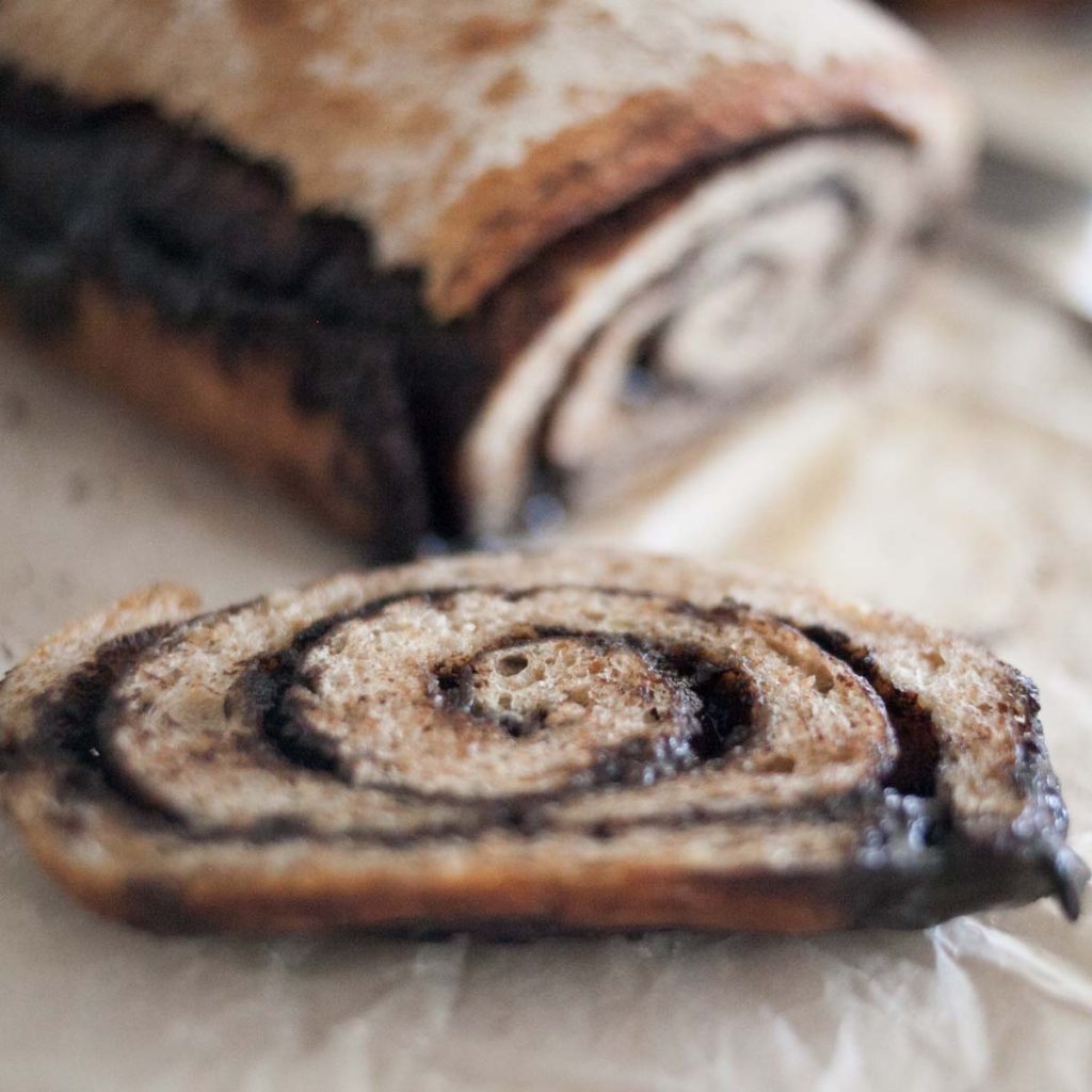 chocolate chai swirl bread close up of end piece with gooey chocolate dripping and rest of loaf in background.