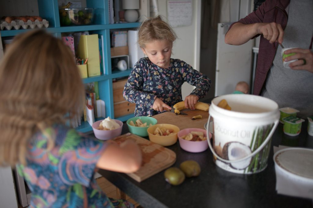 kids cutting fruit at kitchen counter helping make breakfast parfaits