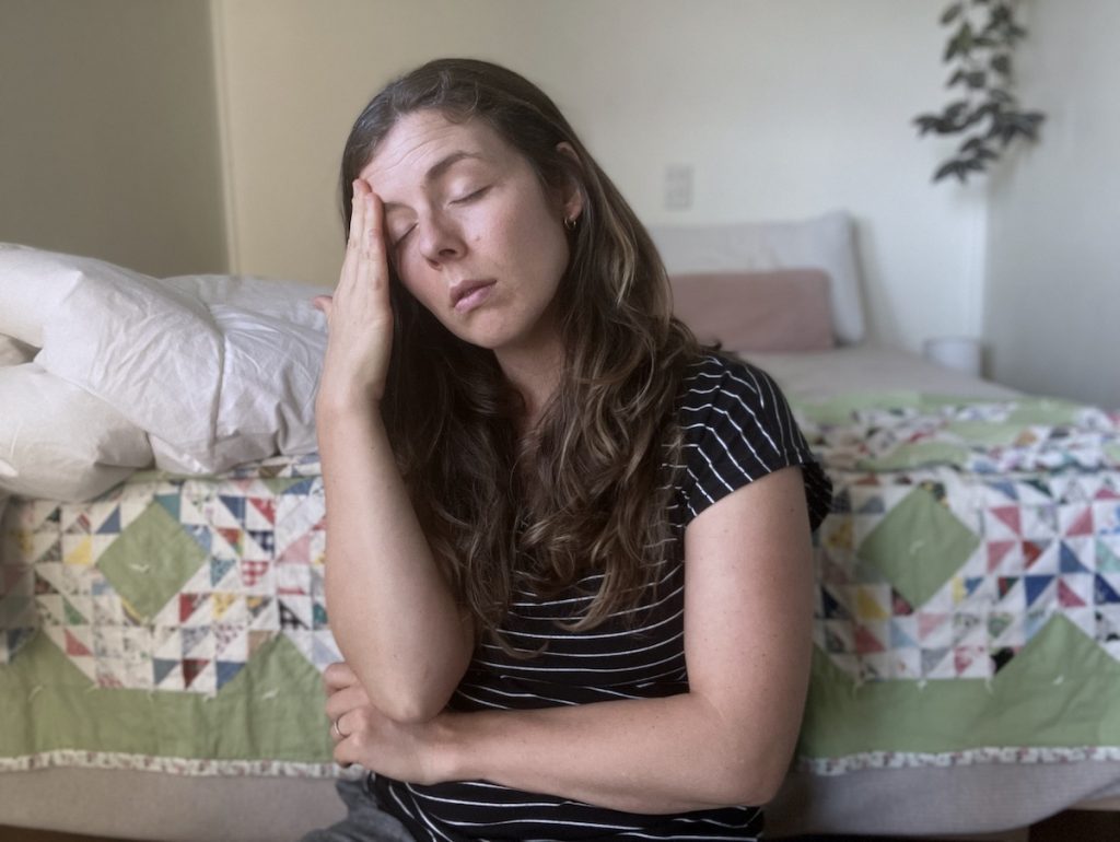 woman rubbing forehead looking overwhelmed and tired