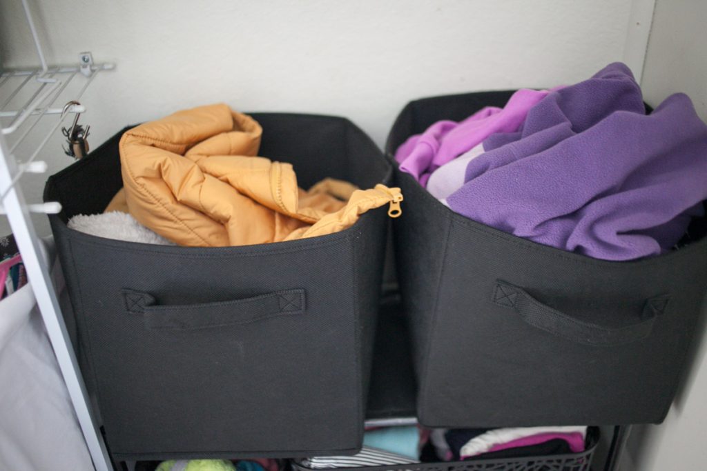 two cloth bins for storage in a shared kids closet