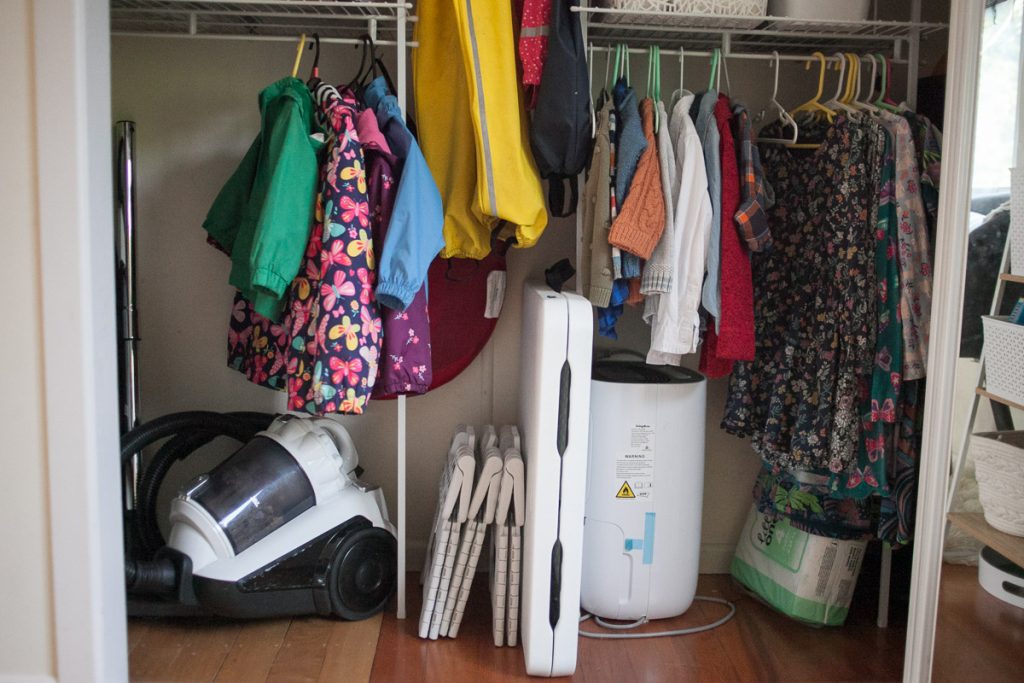 kids rain jackets, sweaters, and dresses hanging on low closet rods