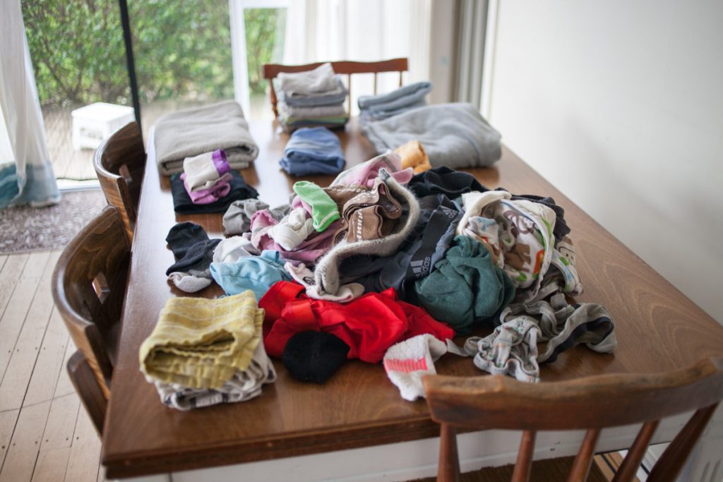 load of clean clothes half folded on dining room table