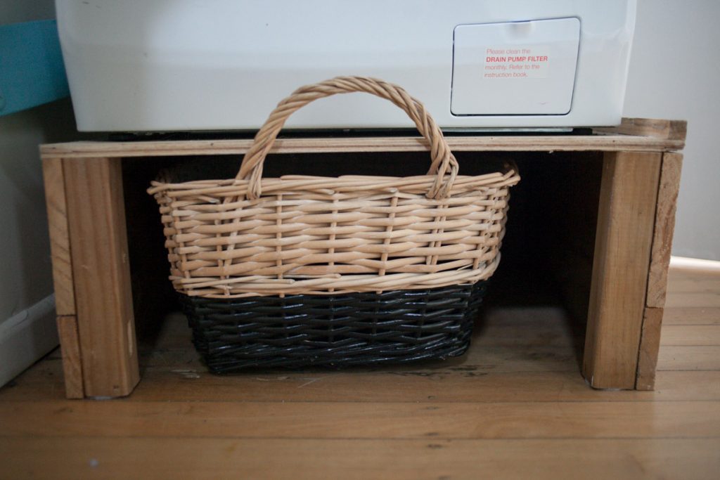 improvised laundry basket under elevated platform for washer