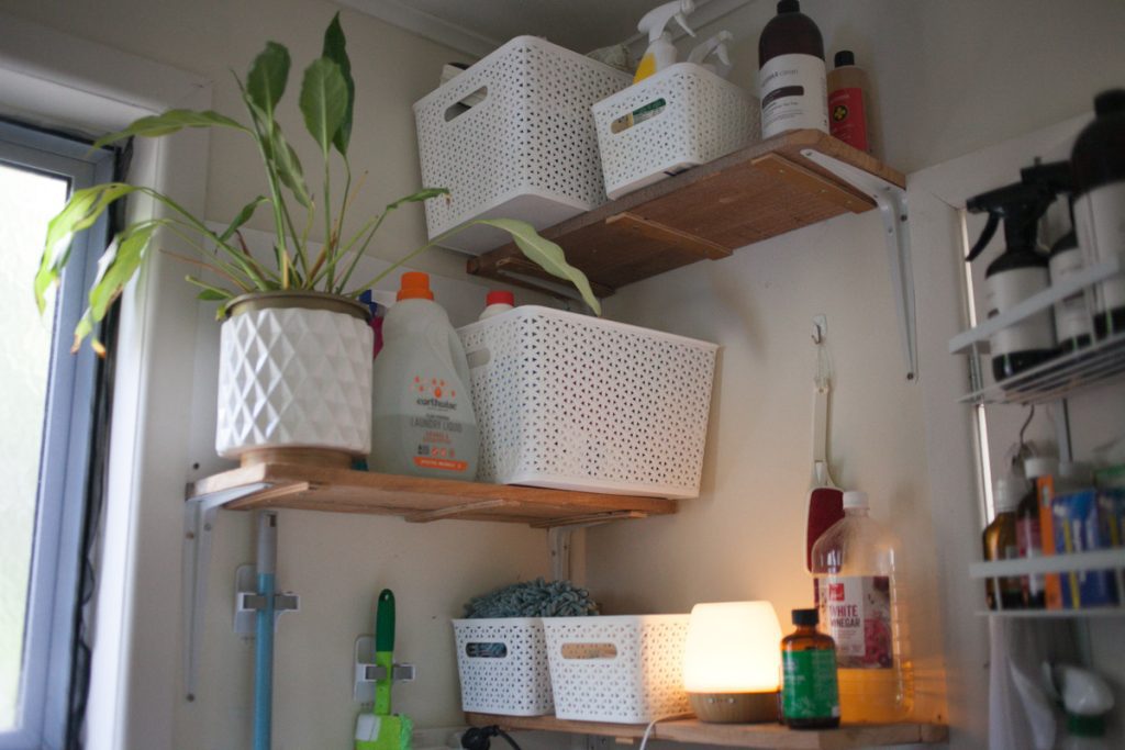 Open shelving in bathroom corner functioning as utility room space