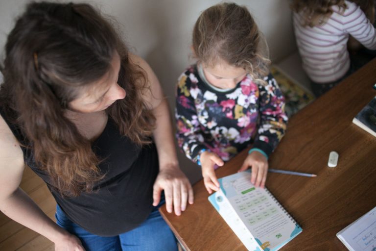 mom homeschooling child at dining room table